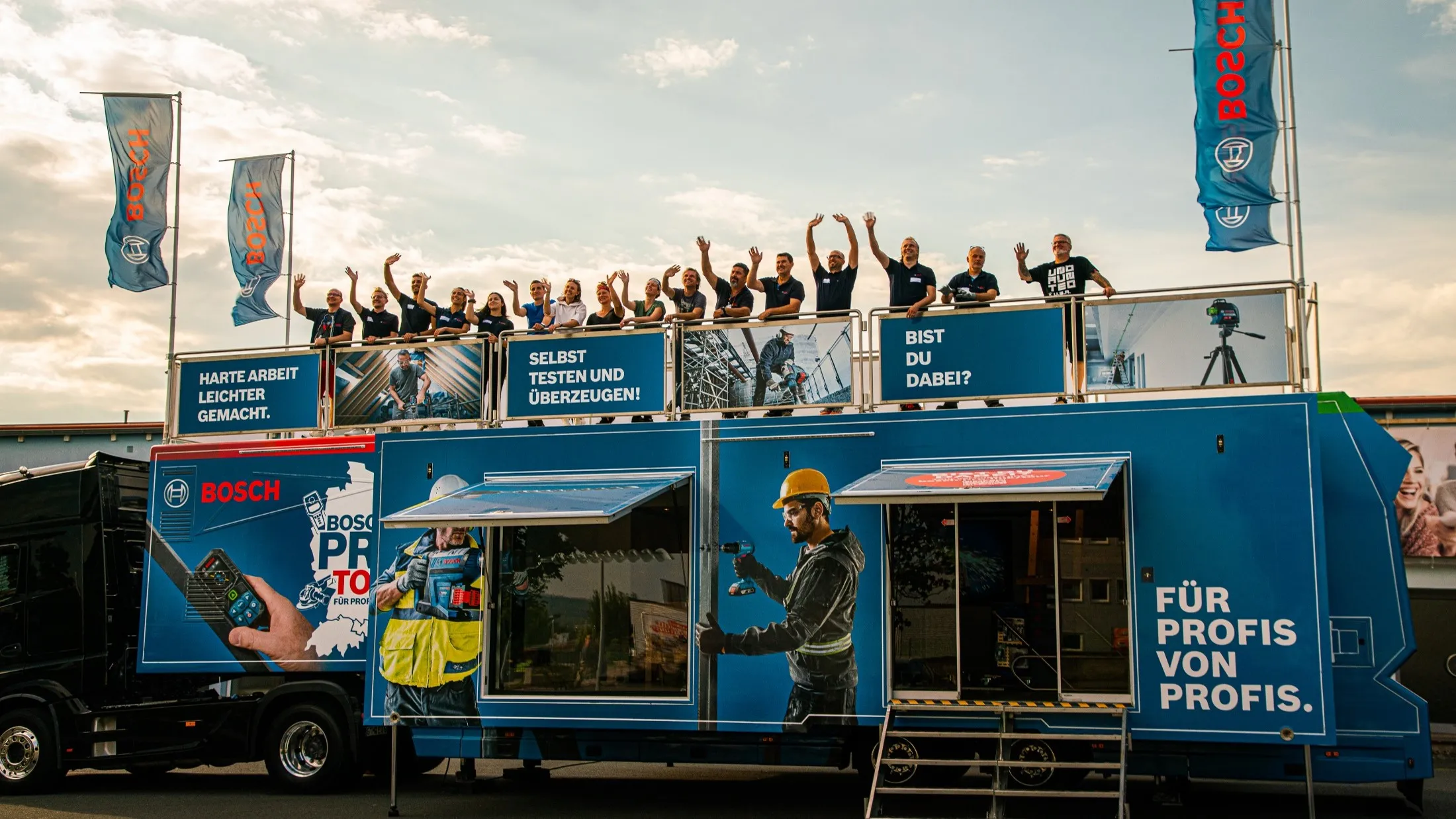 Die Mitarbeitenden der Bosch Pro Tour winken vom Dach des Trucks.