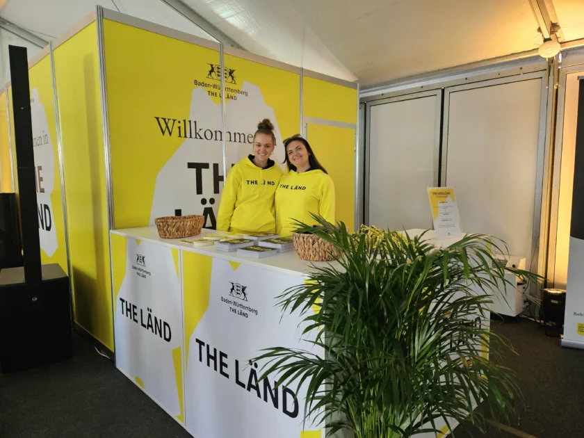 Zwei Mitarbeiterinnen stehen am THE LÄND Stand in gelb.